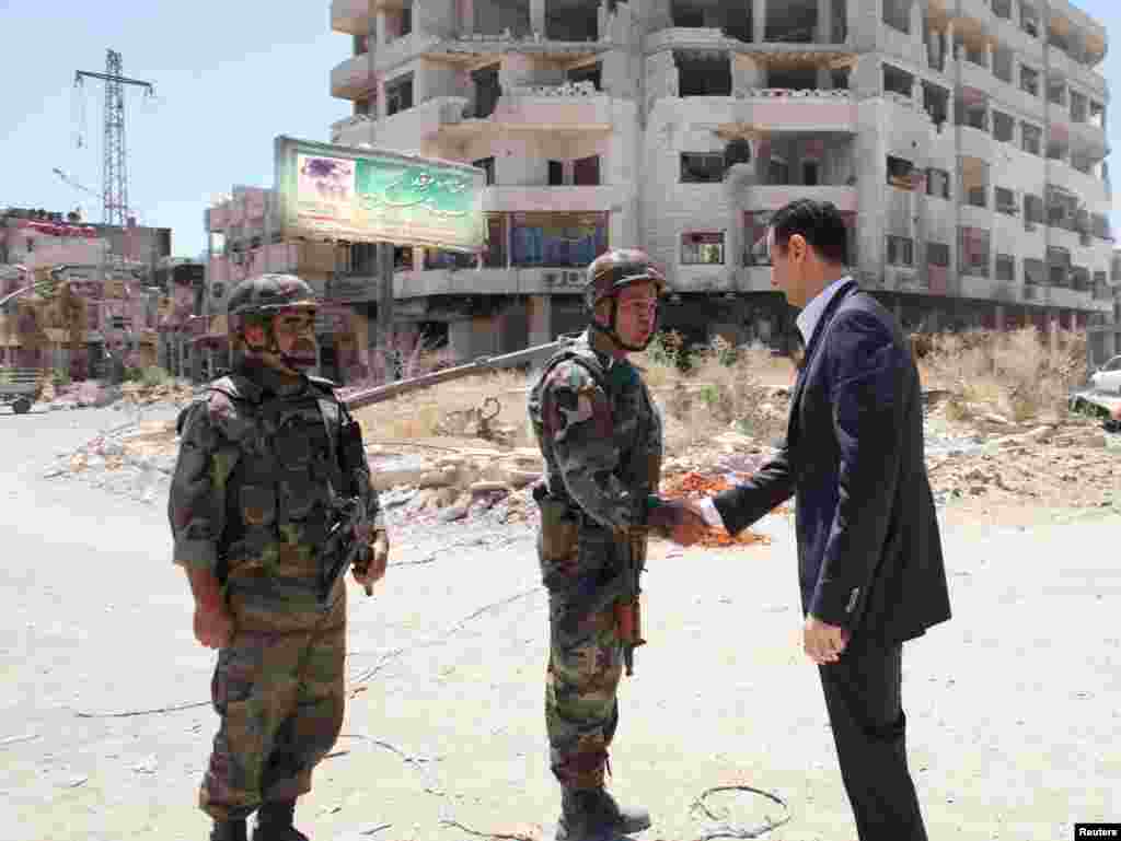 Syria's President Bashar al-Assad shakes hands with military personnel during his visit to a military site at Darya area on the 68th anniversary of army day, August 1, 2013.