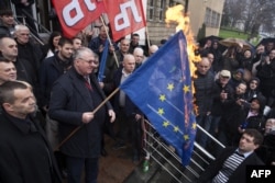 FILE - Serb ultranationalist leader Vojislav Seselj, center, holds a burning European Union flag in front of the war crimes court building in Belgrade, March 10, 2016.