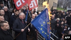 Vojislav Seselj membakar bendera-bendera Uni Eropa dan NATO di luar pengadilan di Beograd hari Kamis (10/3).