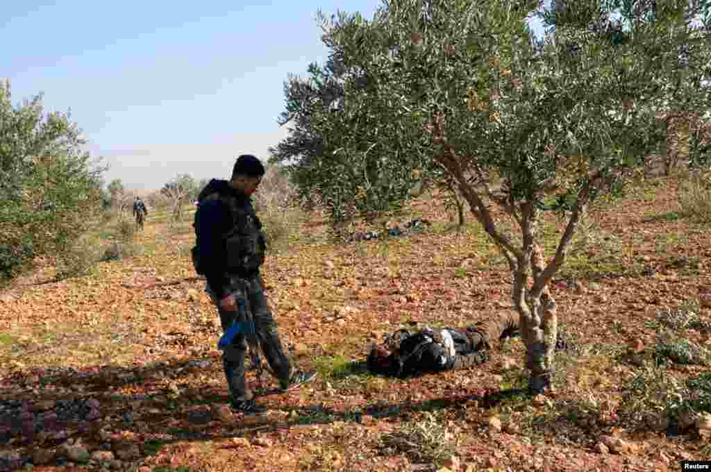 Anggota pasukan yang setia pada Presiden Suriah Bashar al-Assad berdiri dekat jenazah anggota Tentara Pembebasan Suriah yang mencoba menyerang Markas Pertahanan Udara di Tal Hassil (31/12/2012).