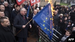 Serb ultranationalist leader Vojislav Seselj holds a burning European Union flag in front of the High Court building in Belgrade, March 10, 2016.