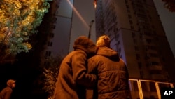 FILE - A couple comforts each other while looking at a fire in a residential building after the attack of Russian drones in Kyiv, Ukraine, Oct. 26, 2024.