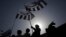 FILE - Supporters of the Jamaat-ud-Dawa Islamic organization are silhouetted against the sun as they raise flags while taking part in a rally in Lahore, May 25, 2012. 