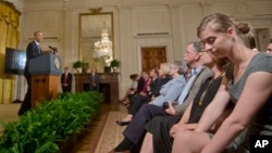 In this Sept. 19, 2014, sexual assault survivor Lilly Jay, right, listens to President Barack Obama, center, announce a 'It's On Us' campaign event in the East Room of the White House. (AP Photo/Pablo Martinez Monsivais)