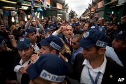 Israeli Prime Minister Benjamin Netanyahu, head of the Likud party, center, is escorted by security guards during a visit to the Ha'tikva market in Tel Aviv, April 2, 2019.