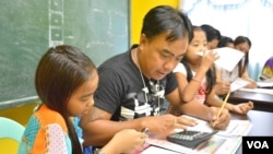 Anh Alvin Balenton cùng hai đứa con út tham dự một lớp học dành riêng cho các ông bố nuôi con đơn thân trong khi vợ làm việc ở nước ngoài, Mabalacat, tỉnh Pampanga, Philippines. (Ảnh: Simone Orendain/VOA)