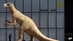 A boy walks by a dinosaur model wearing a face mask, during a partial lockdown to prevent the spread of the coronavirus, at the Museum of Natural History in Brussels, Belgium.