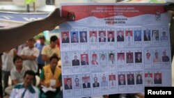 People watch as electoral officials show ballot papers during vote counting at a polling station in Jakarta, April 9, 2014. 
