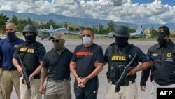 En la imagen divulgada por el Ministerio Público de Honduras, agentes de la Agencia Técnica de Investigación Criminal (ATIC) custodian al narcotraficante hondureño Fredy Donaldo Mármol Vallejo (C), en la Base Aérea Hernán Acosta Mejía, en Tegucigalpa, el 27 de octubre de 2021.