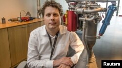 FILE - Rocket Lab CEO Peter Beck sits alongside a Rutherford rocket engine in Auckland, Oct. 20, 2015.