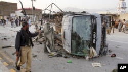 A Pakistani police officer walks past a police vehicle targeted by a suicide bomber in Quetta, April 24, 2018.