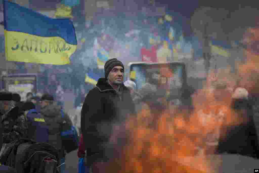 A pro-European Union activist stands while warming himself near a bonfire at a heavily fortified tent camp in the Independence Square in Kiev, Dec. 17, 2013. 