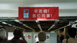 2021年6月17日在香港蘋果日報總部內採訪的記者舉起照相機拍攝管理層向編採職員的打氣橫額 （路透社照片）