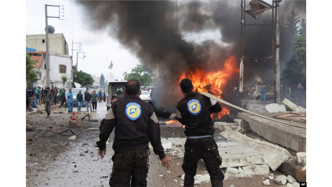This photo provided by Azaz Media Office, a Syrian anti-government activist group, which has been authenticated based on its contents and other AP reporting, shows a Syrian White Helmet civil defense worker extinguishing a burning car at the explosion scene, in Azaz town, north Syria, Wednesday, May 3, 2017.