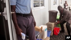 FILE - Liberi'sn Assistant Minister of Health Tolbert Nyenswah (R) washes his hands before a World Health Organization (WHO) announcement in Monrovia, Jan. 14, 2016. The WHO declared an end to the deadliest Ebola outbreak ever after no new cases emerged in Liberia.