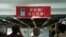 2021年6月17日在香港蘋果日報總部內採訪的記者舉起照相機拍攝管理層向編採職員的打氣橫額 （路透社照片）