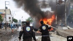 Un Casque blanc syrien éteint une voiture en feu après une explosion dans la ville d'Azaz, au nord de la Syrie, le 3 mai 2017.