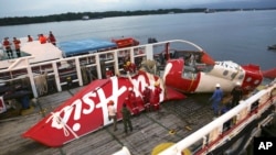 Awak kapal Crest Onyx bersiap mengeluarkan bagian pesawat AirAsia Flight 8501 dari kapal di pelabuhan Kumai di Pangkalan Bun (11/1). (AP/Achmad Ibrahim)