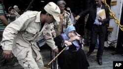 A rebel helps an elderly evacuee Libyan woman on a wheelchair disembarking the Albanian ferry Red Star 1 that evacuated injured people and refugees fleeing the battered city of Misrata, after docking at the port of Benghazi, Libya, April 28, 2011.