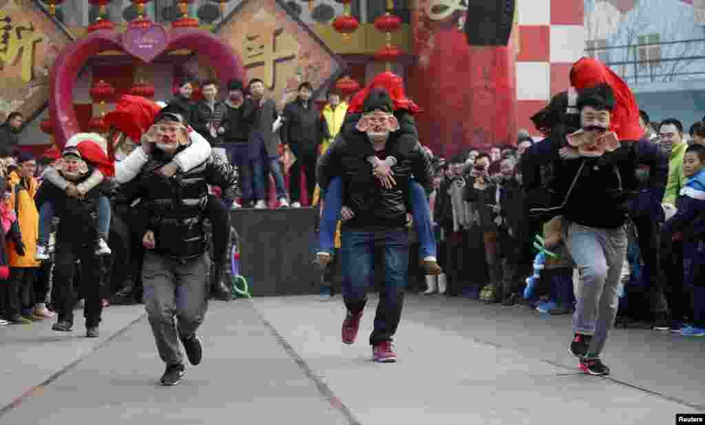 Men wearing pig masks carry their girlfriends on their backs as they run to be selected as finalists during a kissing contest held in celebration of Valentine&#39;s Day at the Happy Valley amusement park in Beijing, China. About 100 couples competed in the contest and an iPhone 5S was presented to the winning couple.