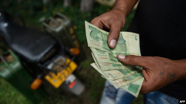 A motorcyclist with two jerry cans attached to his motorbike counts his bond notes at a fuel station, Jan. 11, 2019, in Harare.