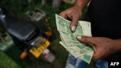 A motorcyclist with two jerry cans attached to his motorbike counts his bond notes at a fuel station, Jan. 11, 2019, in Harare.