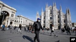 Un hombre con mascarilla pasa ante la catedral gótica del Duomo en Milán, Italia, el domingo 23 de febrero de 2020. (AP Foto/Luca Bruno)