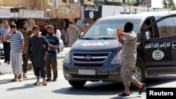 An Islamic State militant uses a loud-hailer to announce to residents of Tabqa city that Tabqa air base has fallen to Islamic State militants, in nearby Raqqa city August 24, 2014.