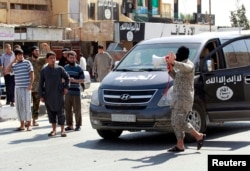 An Islamic State militant uses a bull horn to announce to residents of Tabqa city that Tabqa air base has fallen to Islamic State militants, in nearby Raqqa city, Aug. 24, 2014.