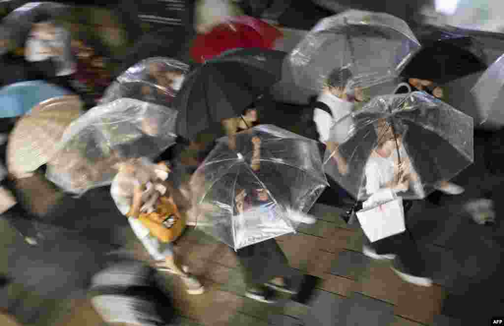 Evening commuters make their way along Omotesando Avenue during a downpour in the Shibuya neighbourhood of Tokyo, Japan.