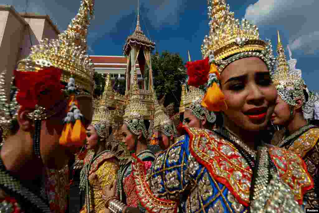 Traditional dancers stand next to the Great Victory Royal Chariot that will carry the late King Bhumibol Adulyadej's body in a giant ornate urn to the cremation site, in Bangkok, Thailand, Sept. 21, 2017.