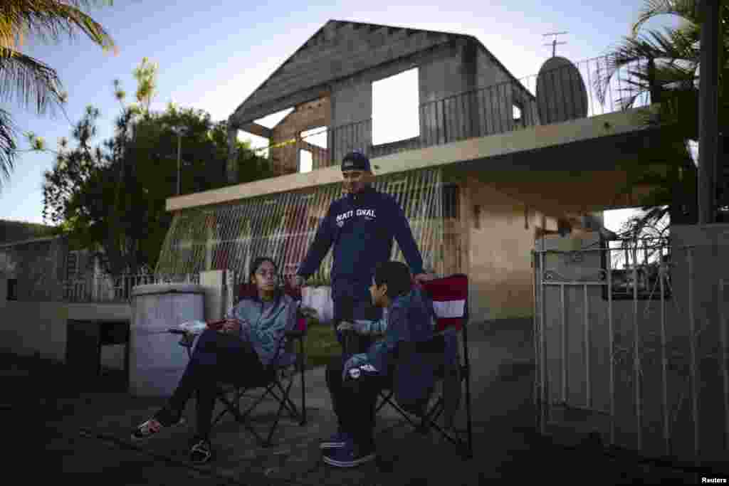 Reynaldo González, centro, sobrino de Nelson Martínez, de 73 años, quien murió después de que un muro se derrumbó durante el terremoto, espera con sus familiares a que se retire el cuerpo de su tío en Ponce, Puerto Rico.