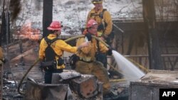 Los bomberos extinguen focos del luego mientras el incendio de Edgehill destruye varias casas y vehículos durante un día caluroso con temperaturas que alcanzan los 107 grados Fahrenheit (41,6 grados Celsius) en San Bernardino, California, el 5 de agosto de 2024. 