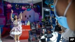 Seorang perempuan merekam video di dekat logo aplikasi Bilibili dan Douyin di sebuah stan dalam pameran telekomunikasi di Beijing, China, pada 28 September 2021. (Foto: AP/Mark Schiefelbein)