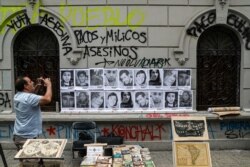 FILE - A man takes a photo of portraits of people that have died during anti-government protests in Santiago, Chile, Nov. 1, 2019.