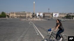 Une femme traverse la place de la Concorde à Paris, en France, pendant qu'elle fait du vélo durant confinement à l'échelle nationale pour contrer le nouveau coronavirus. à Paris, vendredi 10 avril 2020. (AP Photo / Michel Euler)