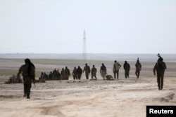 Syria Democratic Forces walk in an area they have taken control of from Islamic State fighters in Hasaka countryside, Syria, Feb. 19, 2016.