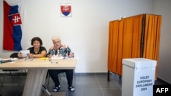 Members of the election committee wait for voters at a polling station in Ocova, near Zvolen, Slovakia, during European Parliament elections on June 8, 2024.