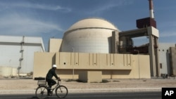 FILE - A worker rides a bicycle in front of the reactor building of the Bushehr nuclear power plant, just outside the southern city of Bushehr, Iran.