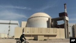 FILE - A worker rides a bicycle in front of the reactor building of the Bushehr nuclear power plant, just outside the southern city of Bushehr, Iran.