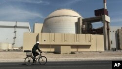 FILE - A worker rides a bicycle in front of the reactor building of the Bushehr nuclear power plant, just outside the southern city of Bushehr, Iran.