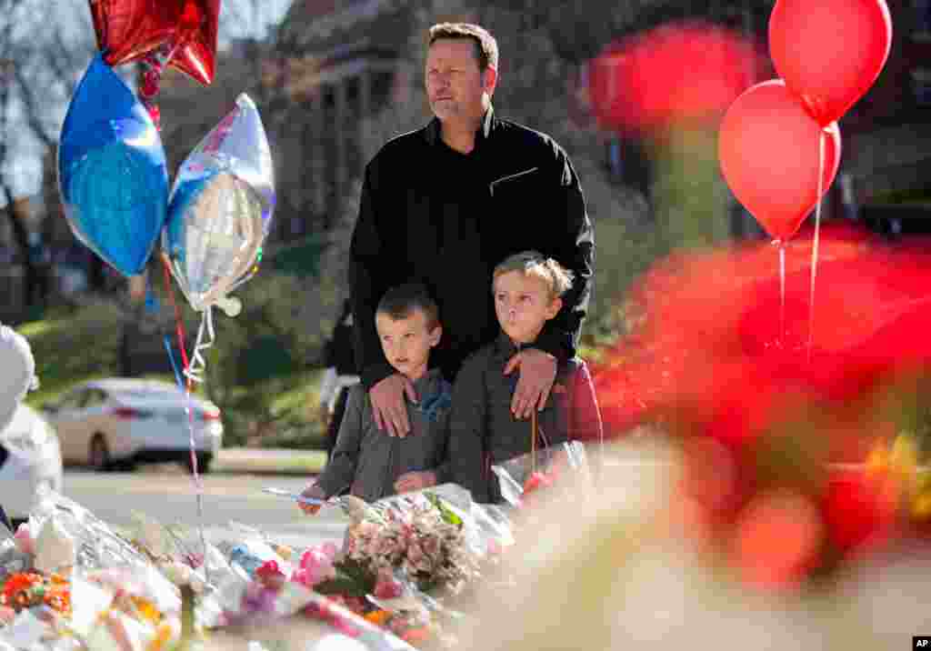 A man and his two sons are seen at a memorial outside the gates of the French Embassy in Washington, Nov. 15, 2015.