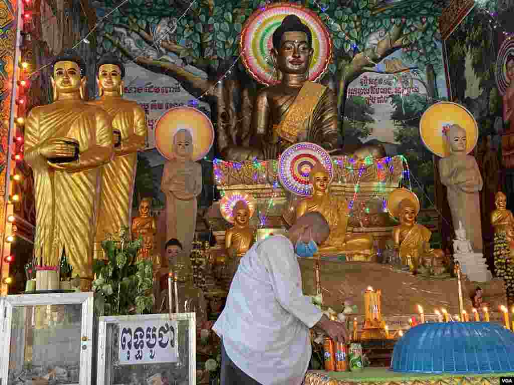 An elderly woman kneels before the Buddha statues on the first day of the Khmer New Year celebration at a pagoda in Phnom Penh, Cambodia, April 14, 2020. (Hean Socheata/VOA Khmer)