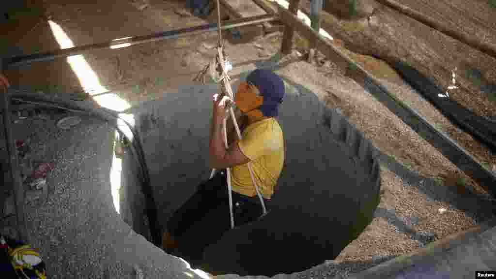 A Palestinian tunnel worker is lowered on a rope into a smuggling tunnel dug beneath the Gaza-Egypt border in the southern Gaza Strip.