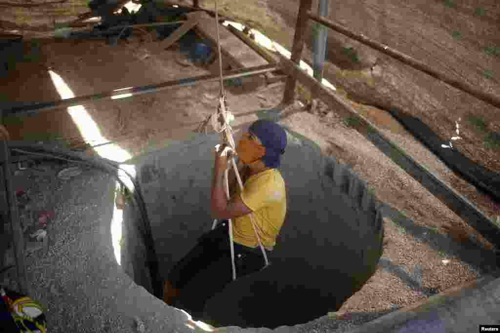 A Palestinian tunnel worker is lowered on a rope into a smuggling tunnel dug beneath the Gaza-Egypt border in the southern Gaza Strip. 