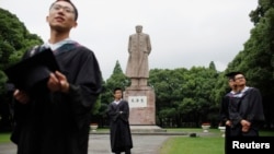 Graduates take pictures in front of the statue of late Chinese leader Mao Zedong after their graduation ceremony at Fudan University in Shanghai June 28, 2013. A record high of 6.99 million students are expected to graduate from college this year which pl