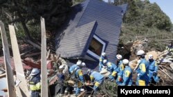 Rescue workers search for survivors from a house damaged by a landslide caused by an earthquake in Atsuma town, Hokkaido, Japan, Sept. 6, 2018.