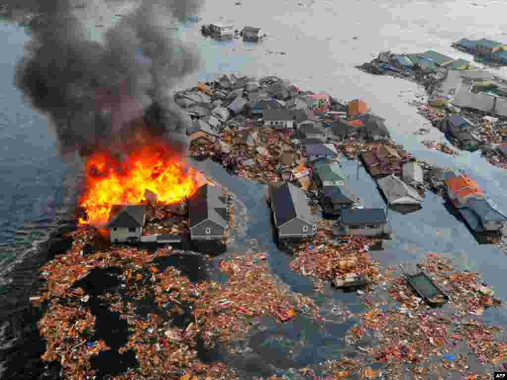 Houses are swept by water following a tsunami and earthquake in Natori City in northeastern Japan March 11, 2011. A massive 8.9 magnitude quake hit northeast Japan on Friday, causing many injuries, fires and a ten-metre (33-ft) tsunami along parts of the