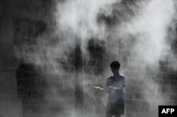 Seorang anak laki-laki mendinginkan diri di tempat pemandian umum di pinggir Sungai Seine, Paris, 25 Juli 2019. (Foto: AFP)