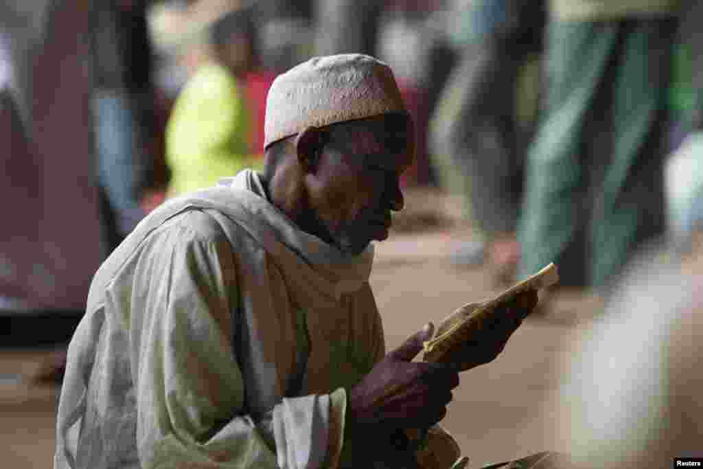 A man prays while reading verses from the Koran in a hangar at the airport of the capital Bangui January 30, 2014. The hangar is used to shelter internally displaced Muslims fleeing the continuing sectarian violence and those waiting to be evacuated by ai